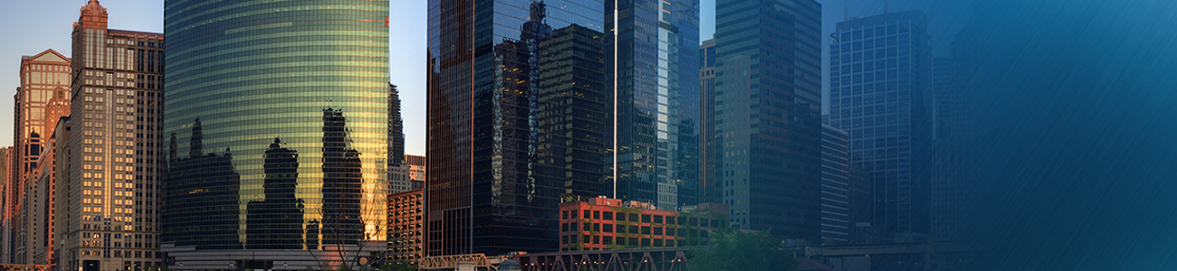 Modern city skyline reflecting the sunset on a riverfront, showcasing a mix of architectural styles.