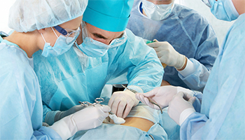 A surgical team in blue scrubs performing an operation.